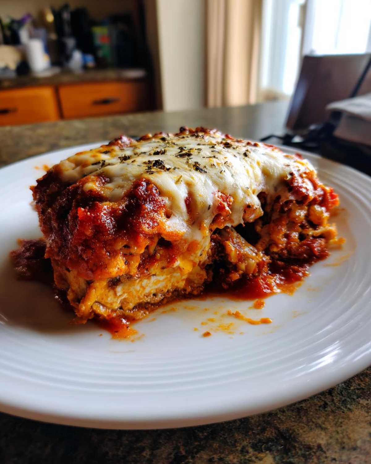 A slice of crispy baked eggplant parmesan with layers of eggplant, sauce, and melted cheese.