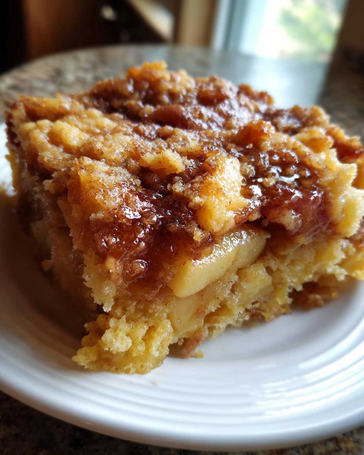 A slice of Crockpot apple dump cake on a white plate, showcasing the apple filling and crumbly topping.