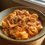 A bowl of creamy crockpot chicken tortellini, featuring tender chicken and cheese-filled pasta in a tomato-based sauce.