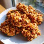 A plate of freshly baked, golden brown granola clusters, perfect for a healthy snack or breakfast.