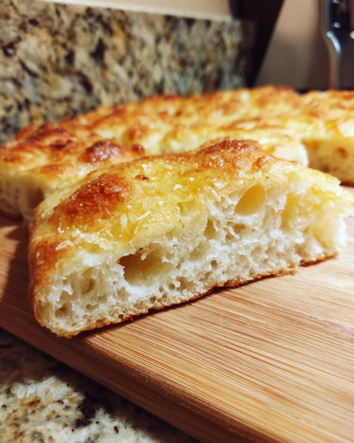 Close-up of a slice of garlic keto flatbread showing the texture, on a wooden board.