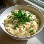 A bowl of creamy garlic parmesan risotto, garnished with fresh parsley and grated parmesan cheese.