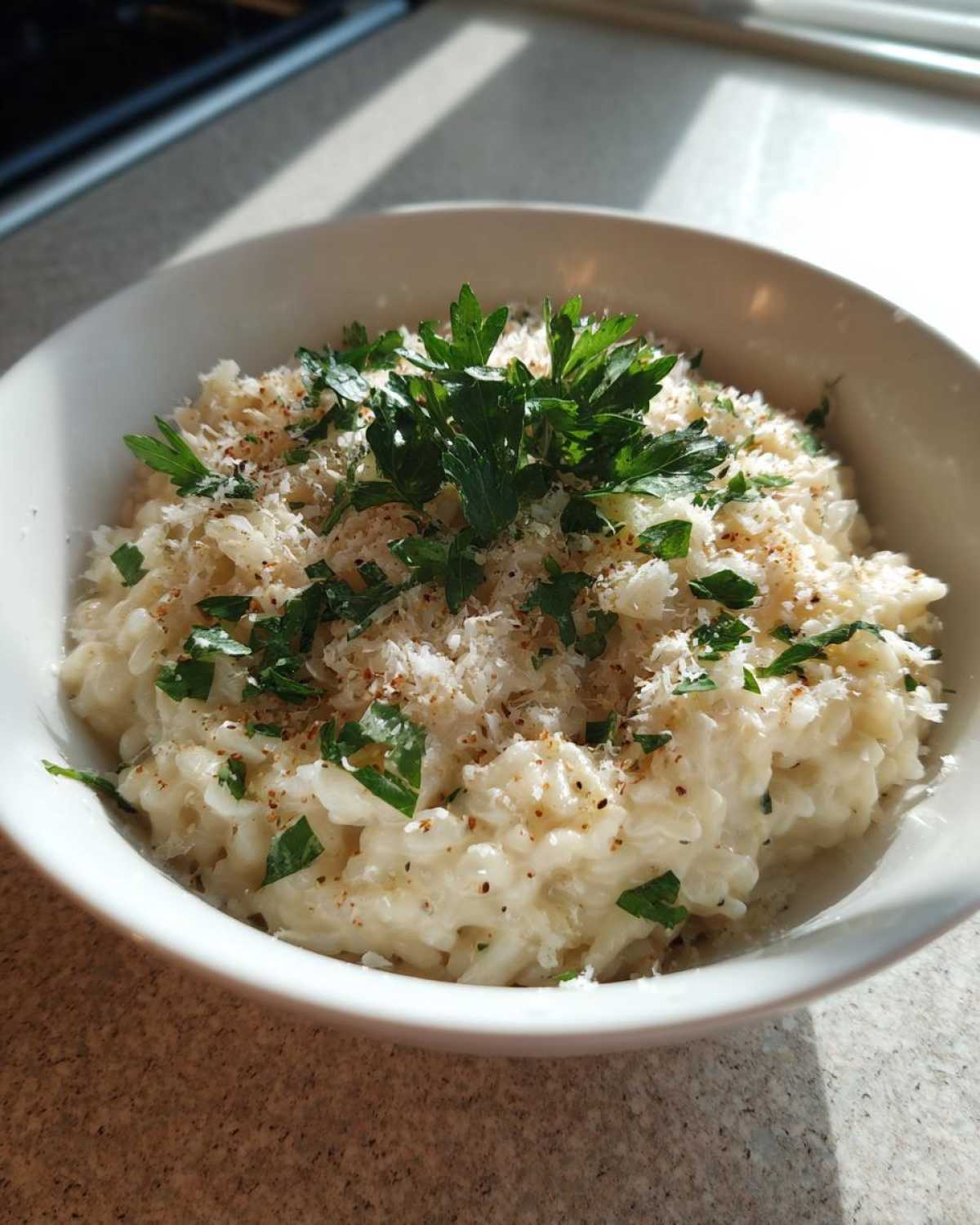 A bowl of creamy garlic parmesan risotto topped with parmesan cheese and fresh parsley.