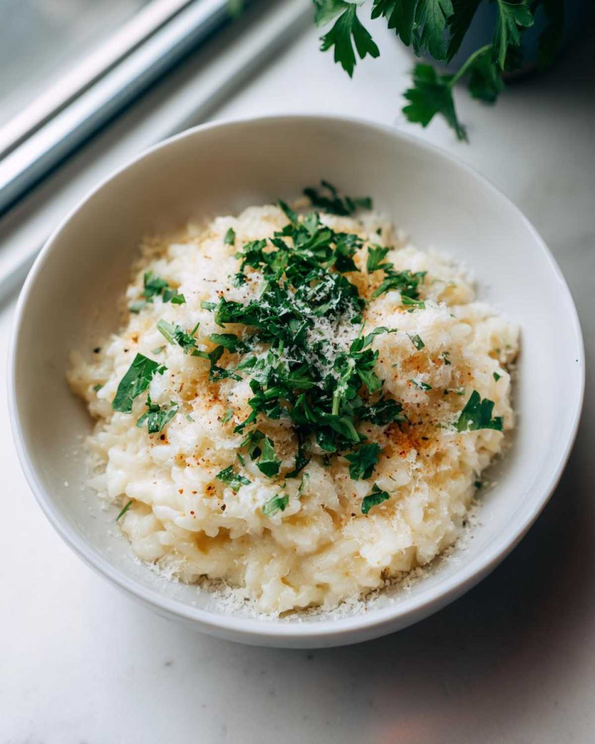 A bowl of creamy garlic parmesan risotto, topped with fresh parsley and grated parmesan cheese.