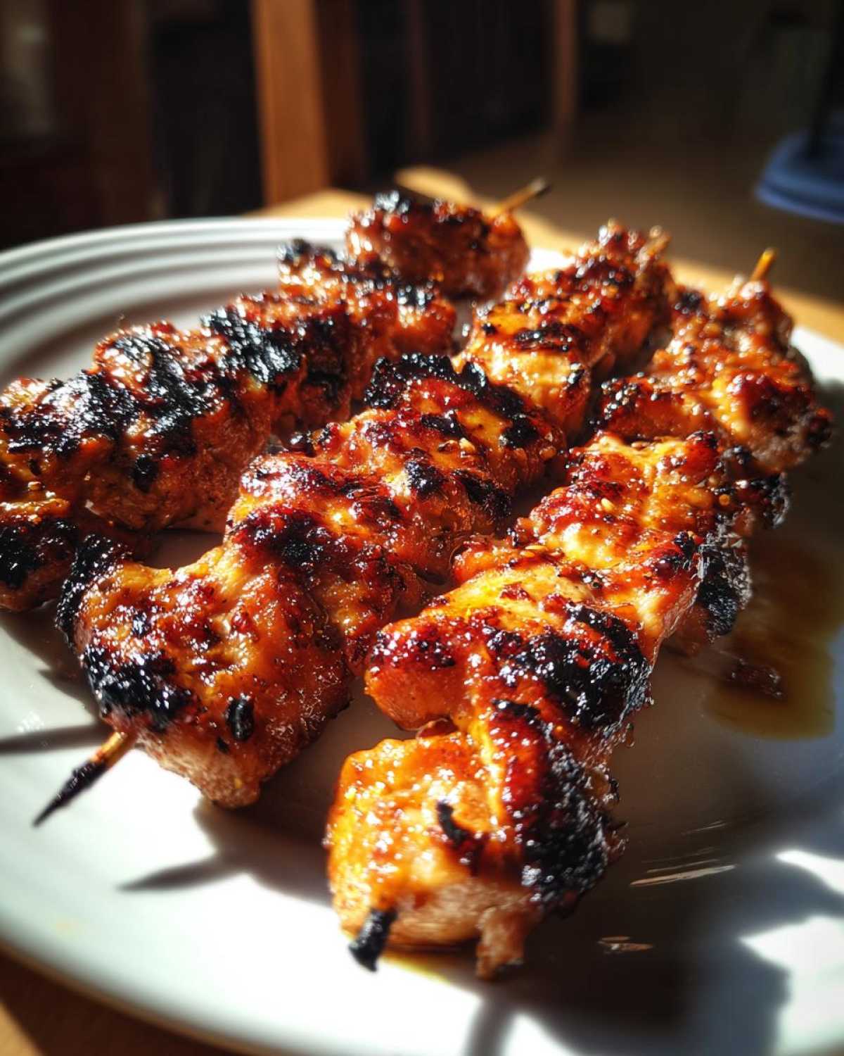 Close-up of grilled asian chicken skewers on a white plate, showing the caramelized glaze.