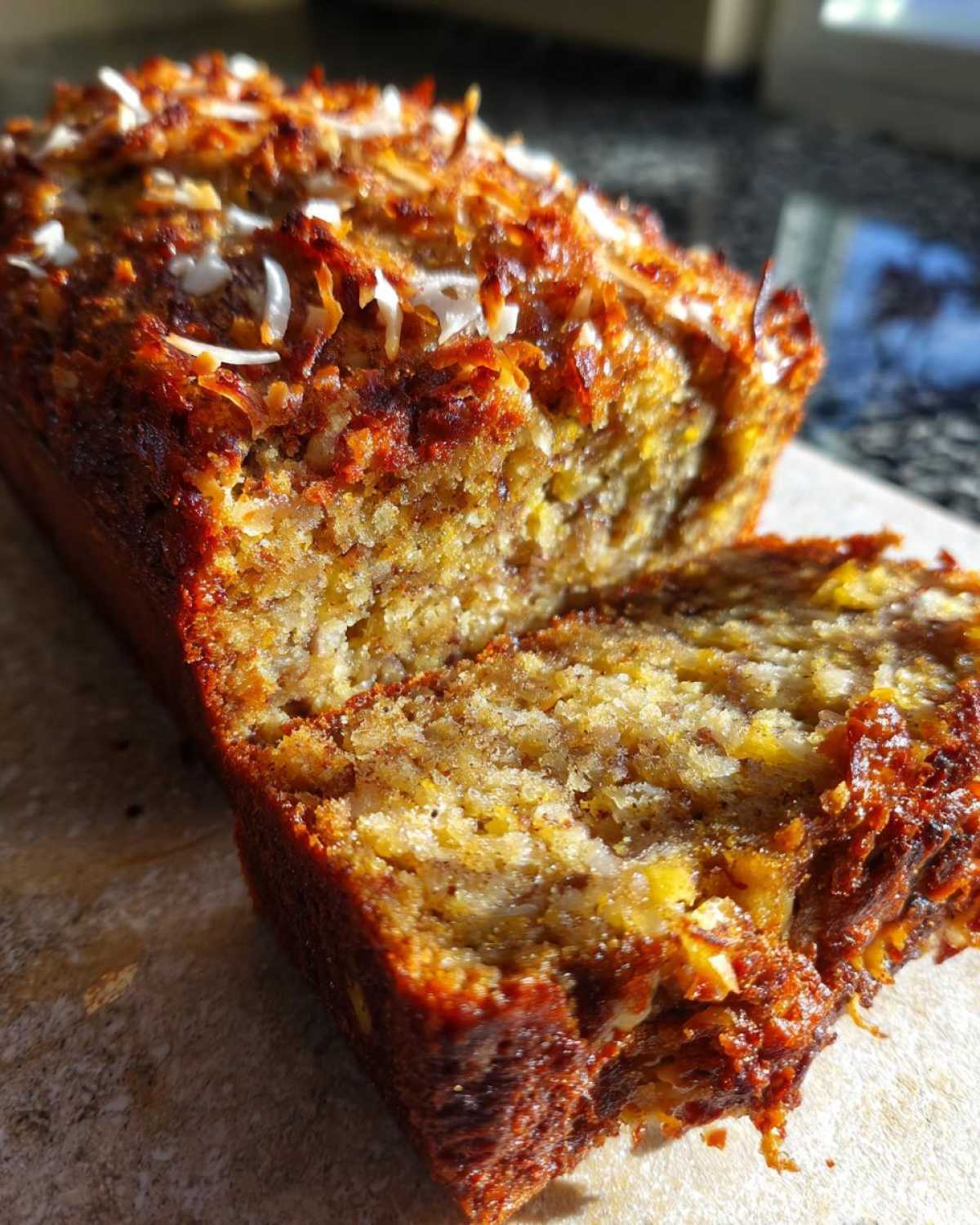 A close-up of freshly baked Hawaiian banana bread topped with toasted coconut flakes.