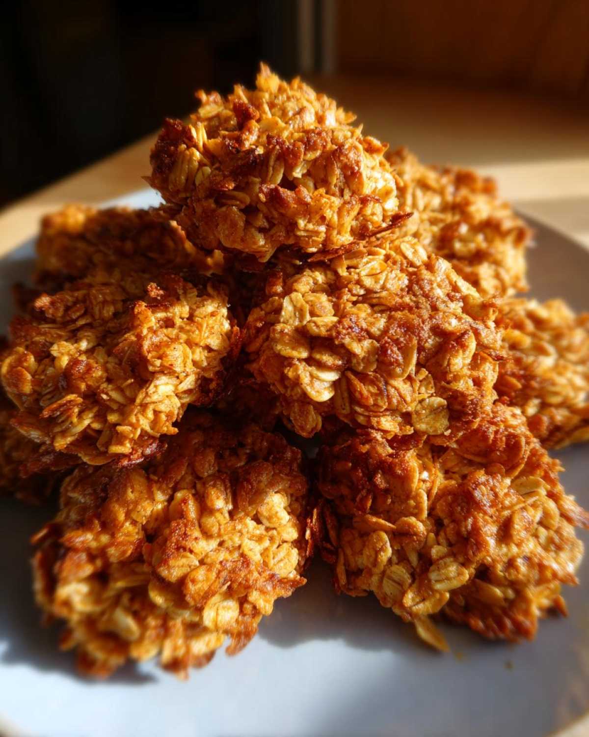 A pile of golden brown, homemade granola clusters on a light blue plate, ready to be enjoyed.