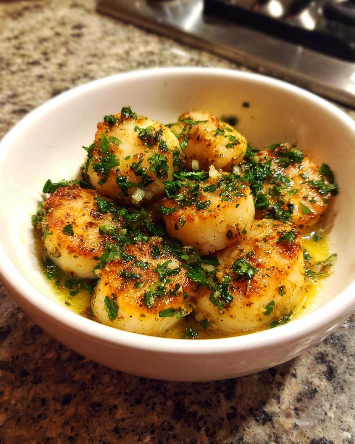 Bowl of perfectly seared lemon garlic scallops, garnished with fresh herbs and a light sauce.