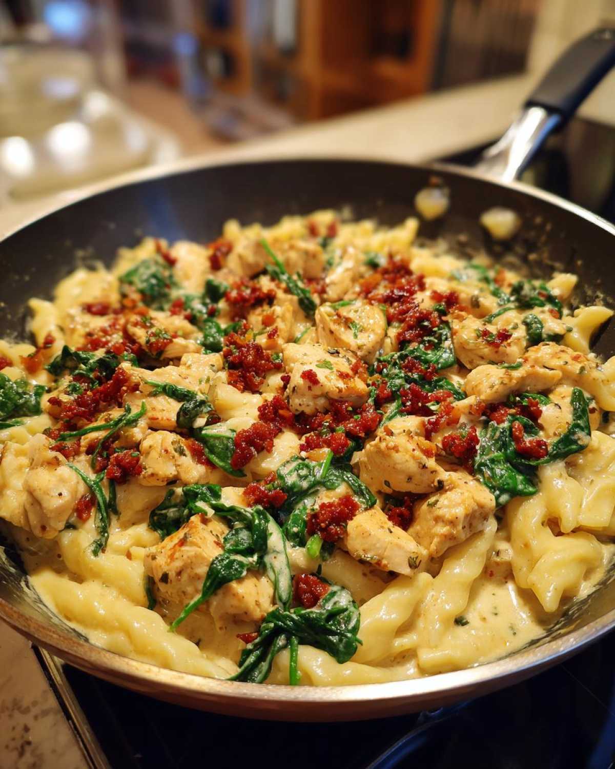 A pan filled with creamy pasta with chorizo and chicken, topped with spinach for a flavorful meal.