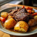 A hearty plate of pot roast with potatoes and carrots, glistening with savory gravy.
