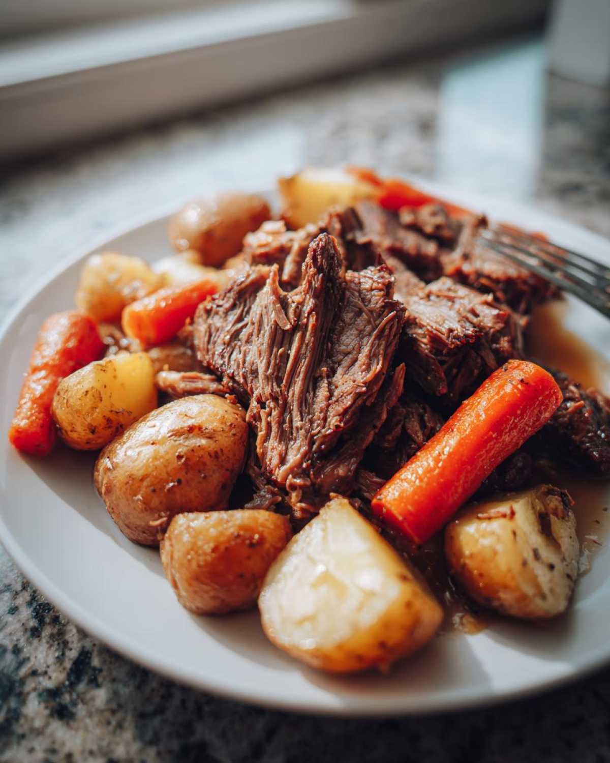 A plate of delicious pot roast with potatoes and carrots, ready to be served. Hearty pot roast with potatoes and carrots.