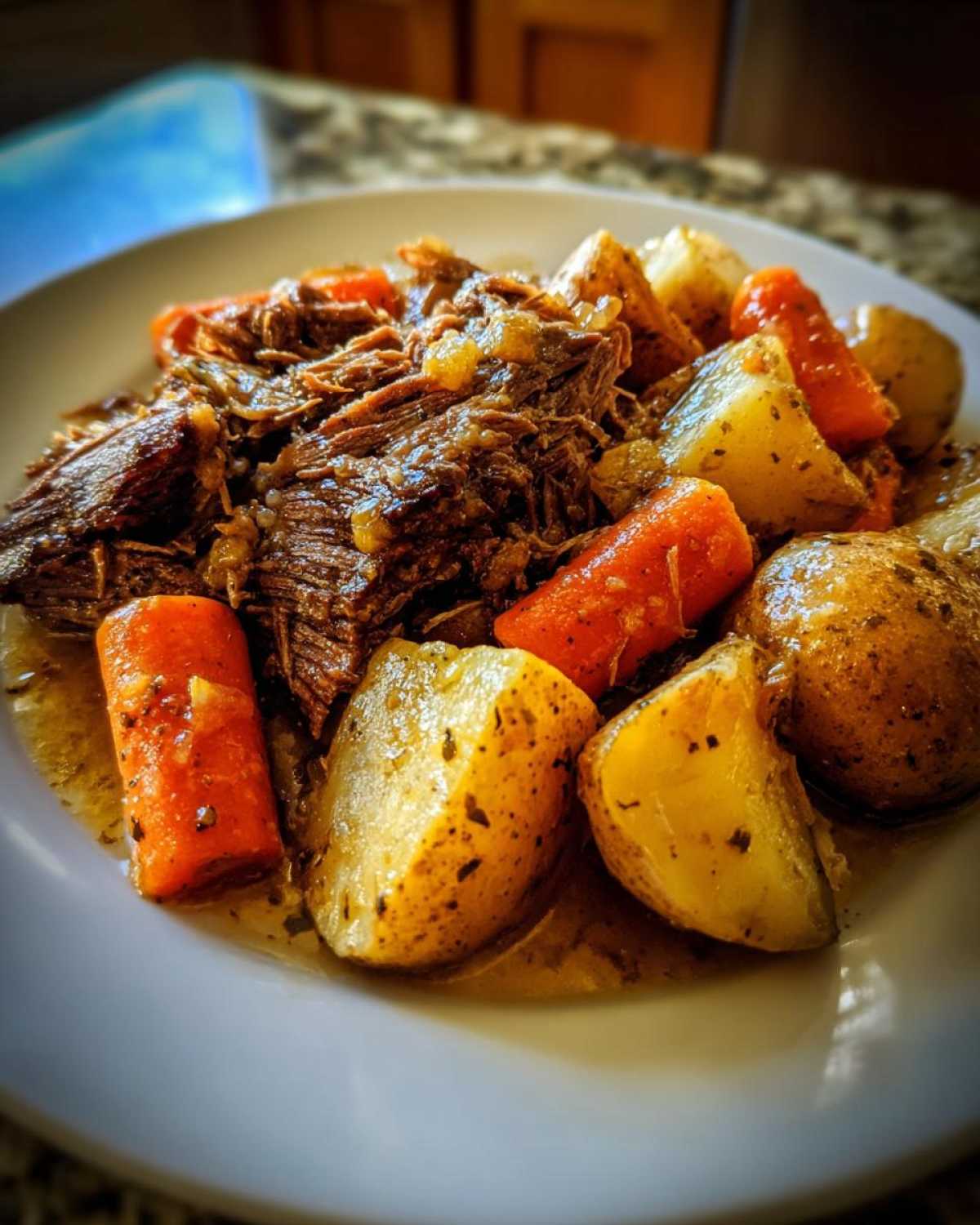 A plate of delicious pot roast with potatoes and carrots, ready to be enjoyed.