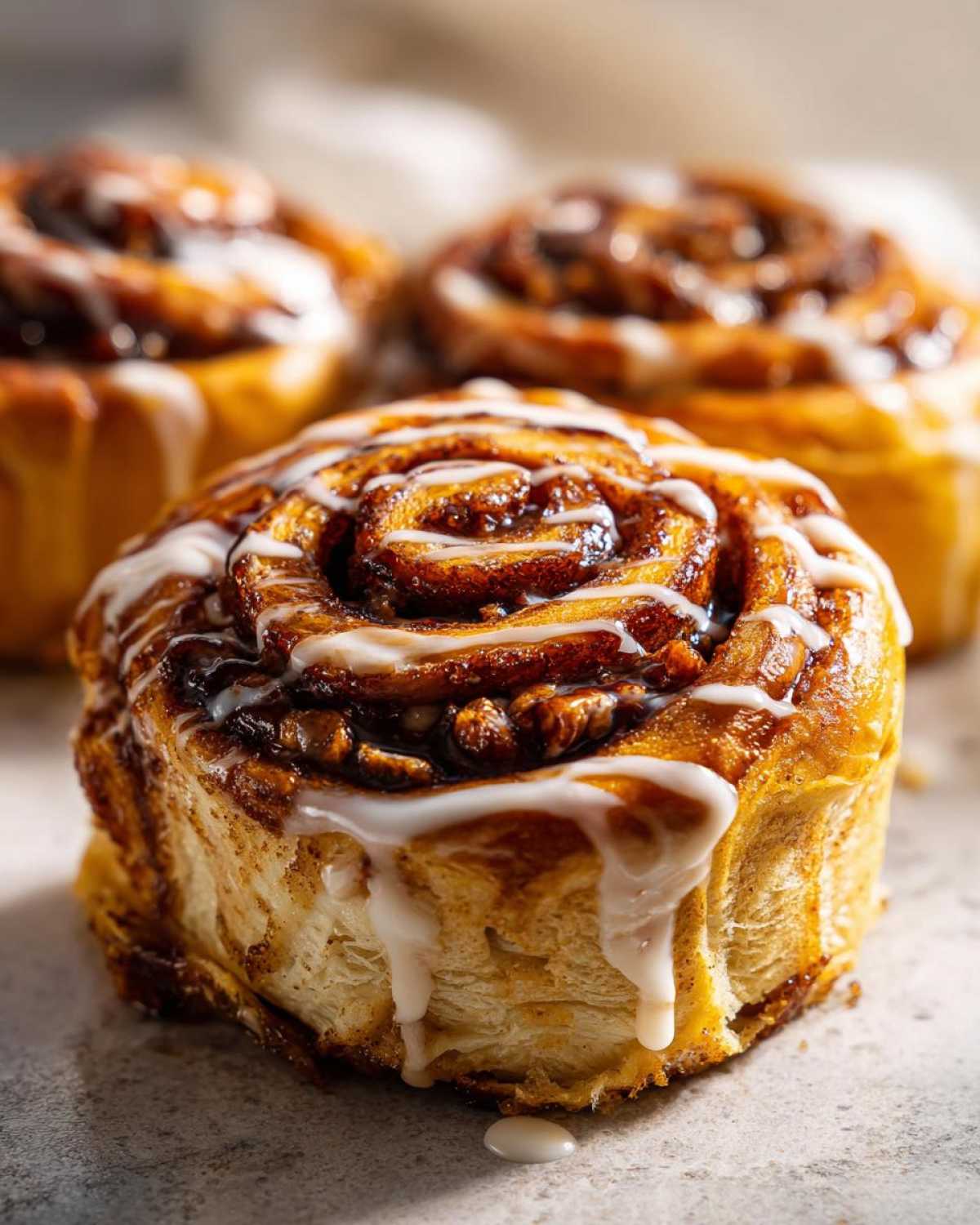 Close-up of a glazed pumpkin cinnamon roll casserole with a swirl pattern and dripping icing.
