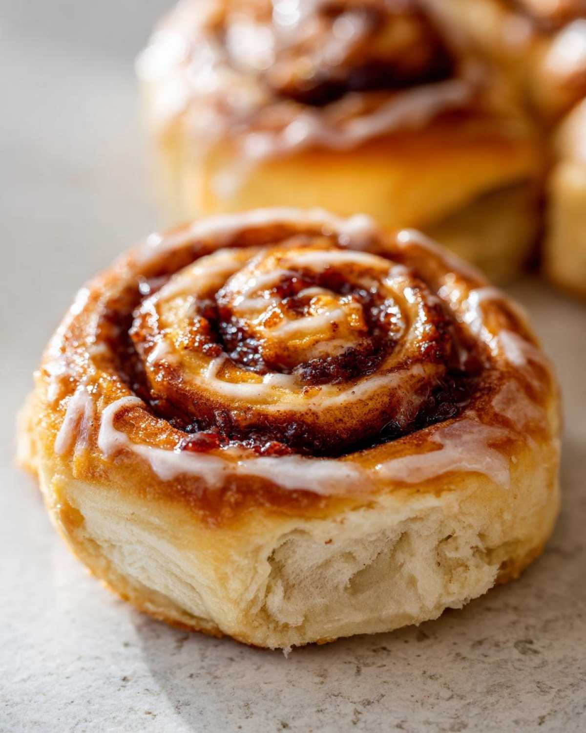 A close-up of a glazed pumpkin cinnamon roll casserole roll, showcasing its swirls and texture.