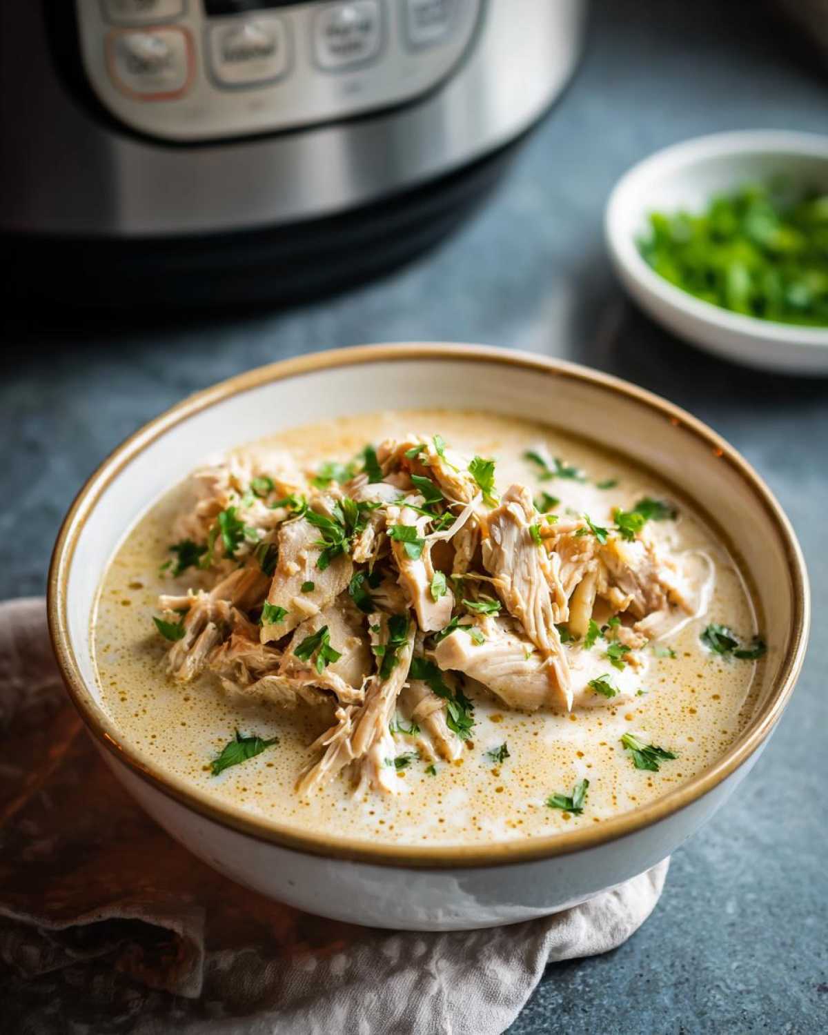 A bowl of creamy slow cooker white chicken chili topped with shredded chicken and fresh cilantro.