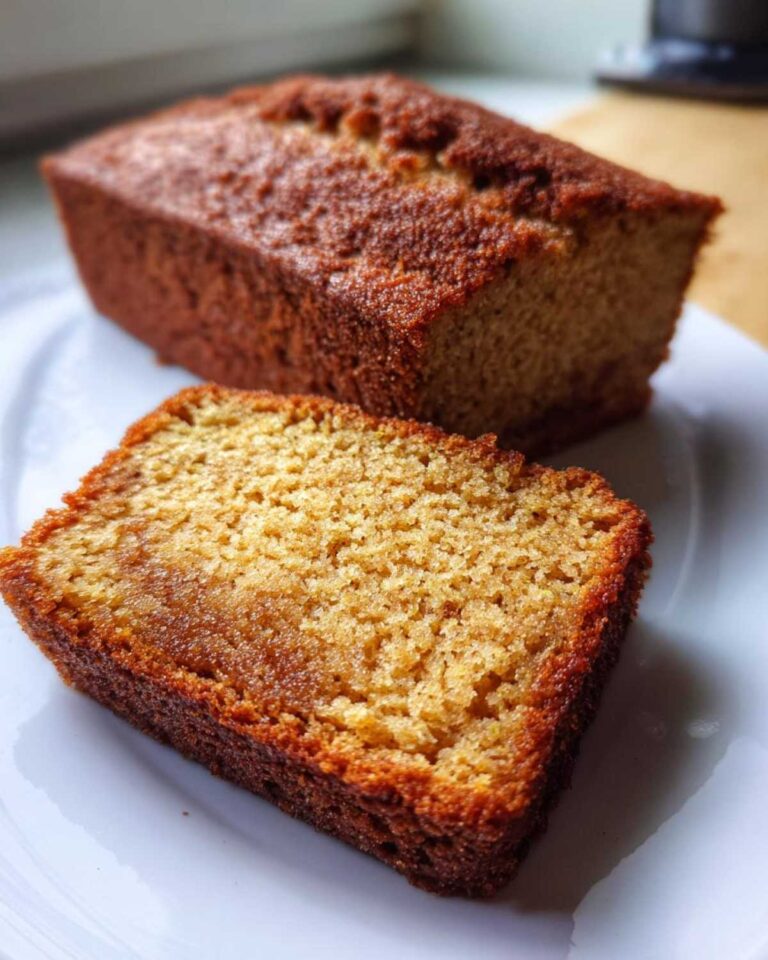 A loaf of snickerdoodle zucchini bread with a slice cut, showing the moist crumb.