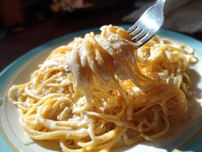 Close-up of spaghetti with creamy alfredo sauce being lifted with a fork. Delicious and easy alfredo sauce recipe.