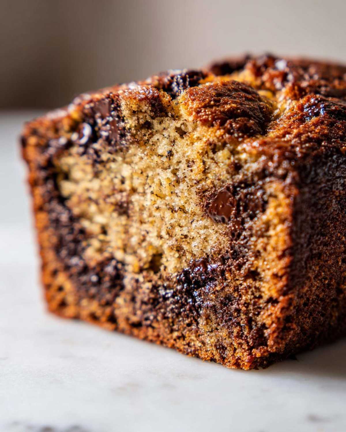 Close-up of a moist slice of chocolate chip banana bread, showing the texture and chocolate chips.