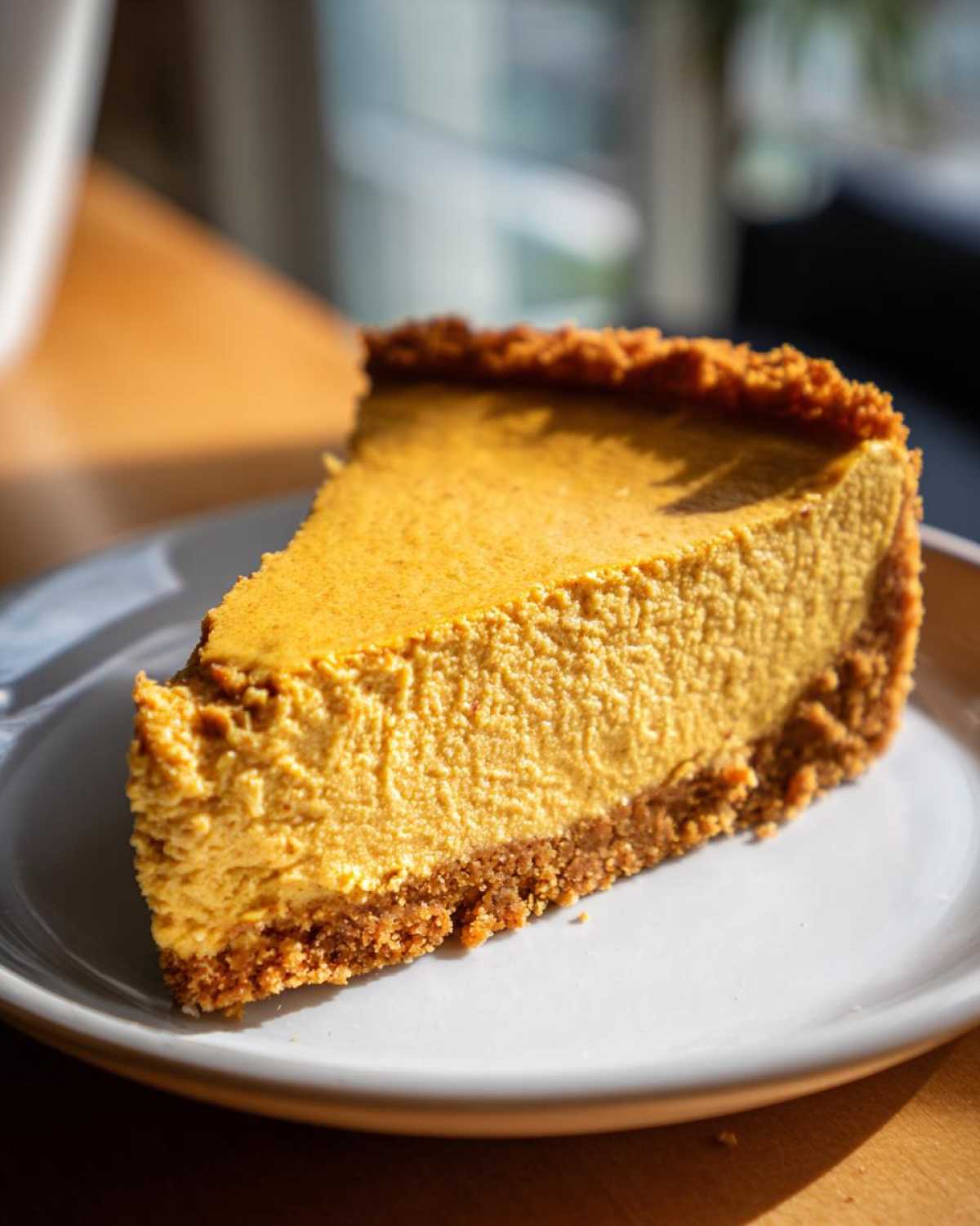 A delicious slice of Keto pumpkin cheesecake with a golden crust, served on a white plate.