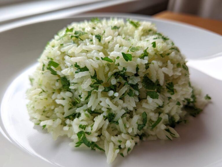 A perfectly molded mound of bright cilantro lime rice garnished with fresh green herbs on a white plate.