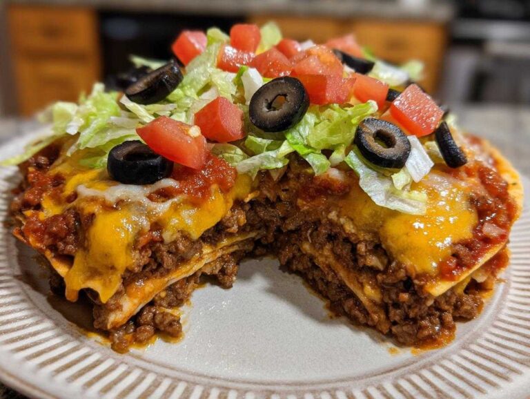 A slice cut from a layered mexican pizza showing ground beef, melted cheese, salsa, lettuce, tomatoes, and black olives.