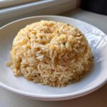 A perfectly molded mound of glistening, savory butter rice served in a white bowl.