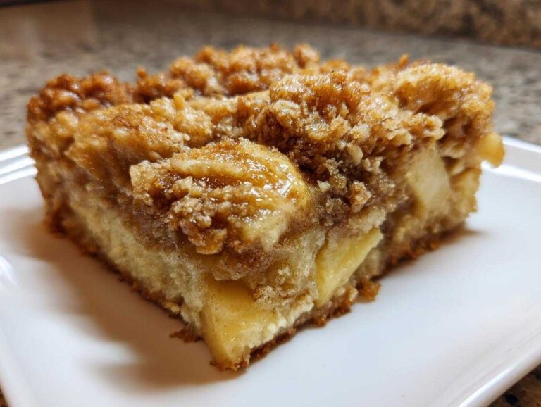 Close-up of a square slice of apple baked oatmeal featuring a thick, sugary cinnamon crumb topping and visible apple chunks.
