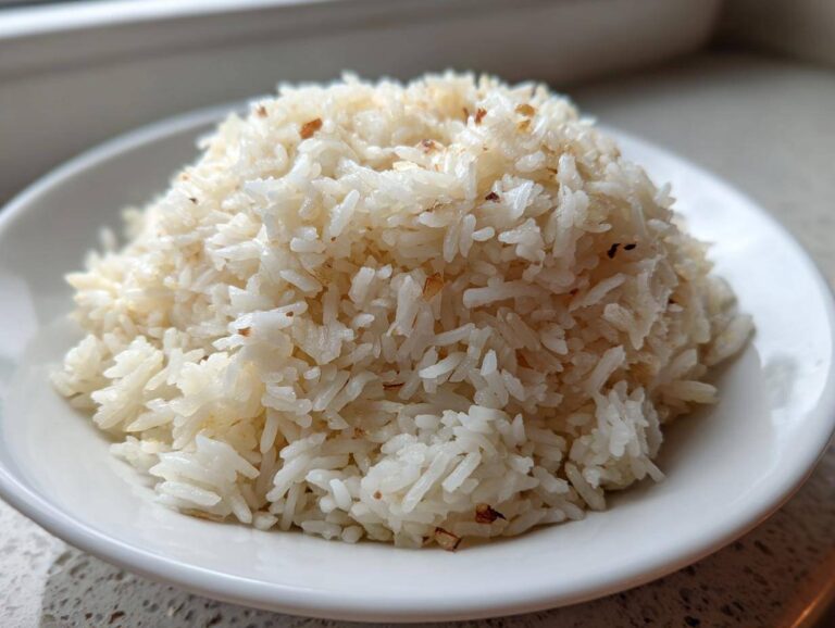A close-up, featured image of fluffy, perfectly cooked butter rice mounded high in a small white bowl.