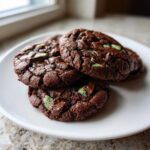 A stack of three rich, dark chocolate Andes mint cookies featuring visible green mint pieces and melted chocolate chips.