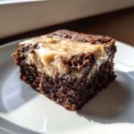 A single square of rich, dark chocolate banana bread brownies topped with a thick, gooey caramel swirl.