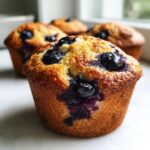 Close-up of a perfectly baked blueberry cottage cheese muffin with visible blueberries on top and bursting through the golden crust.