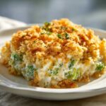 A close-up serving of creamy broccoli rice casserole topped with golden brown breadcrumbs and fresh herbs.