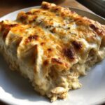 Close-up of a serving of creamy white sauce chicken enchiladas baked with melted, bubbly cheese on top.