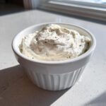 A close-up of creamy horseradish sauce topped with black pepper in a small white bowl.
