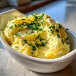 Fluffy mashed potatoes topped with melted butter and fresh parsley, implying the use of garlic butter.