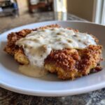 A close-up of a perfectly breaded and fried chicken fried steak smothered in creamy, peppery sausage gravy.