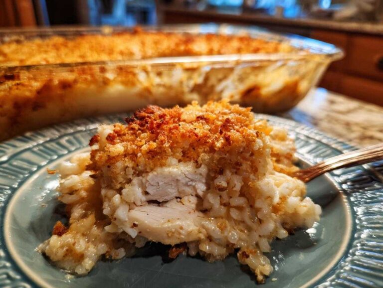 A close-up serving of creamy chicken and rice with a golden brown, crispy topping, fresh from the pan.