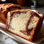 A close-up view of thick slices of moist cinnamon bread showing rich brown cinnamon swirls throughout the light crumb.