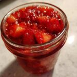 Close-up of a glass jar filled with vibrant, chunky strawberry freezer jam.