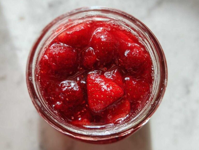 Overhead close-up view of chunky strawberry freezer jam filled to the top of a glass jar.