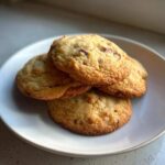 A stack of four golden brown, chewy cake mix cookies with visible chocolate chips on a white plate.