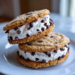 Two stacked cannoli cookies sandwiches filled with creamy ricotta filling and mini chocolate chips.