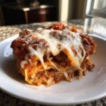 A gooey, cheesy slice of crockpot ravioli lasagna covered in melted mozzarella and meat sauce.