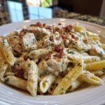 Close-up of creamy chicken bacon ranch pasta featuring penne noodles, diced chicken, and crumbled bacon.