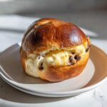 A single, golden-brown chocolate chip vanilla custard brioche filled with creamy vanilla custard and dark chocolate chips.