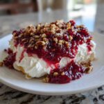 A close-up serving of cranberry cream cheese dip topped with rich cranberry sauce and chopped pecans.