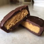 Close-up of homemade peanut butter cups cut in half, showing thick chocolate shell and creamy peanut butter filling.