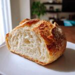 Close-up of a freshly baked loaf of crusty italian bread, cut in half showing an airy interior.
