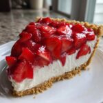 A close-up of a slice of easy strawberry pie with a graham cracker crust and creamy filling.