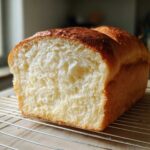 Close-up of a freshly baked loaf of yeast bread sliced open, showing a soft, fluffy interior and golden crust.